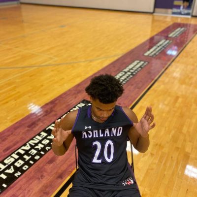 Maceo Williams is sitting in a chair showing his jersey.